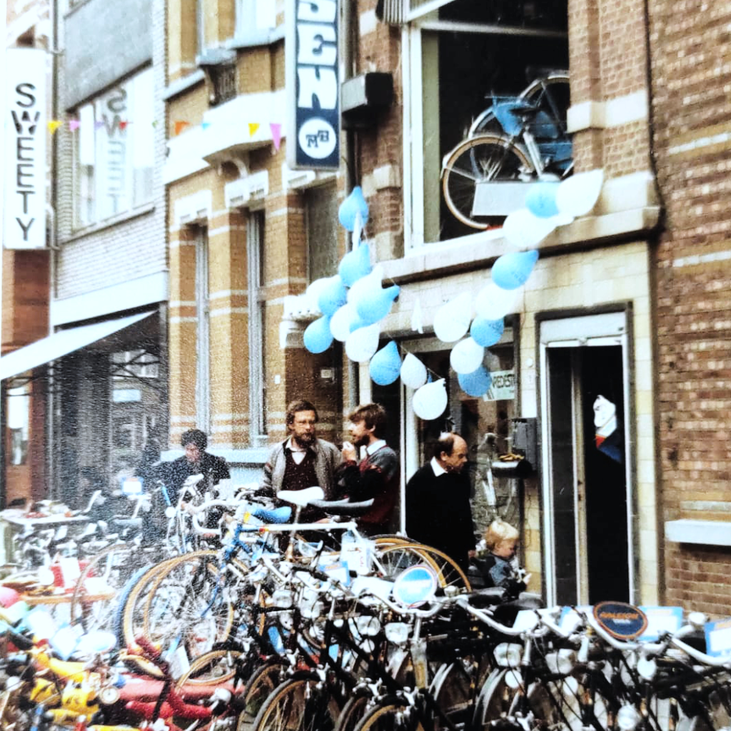 Hier ziet een foto met veel fietsen die uitgestald staan bij Fietsen MB in de jaren tachtig. Dit is tijdens de Deurnestraat feesten die toen jaarlijks gehouden werden.