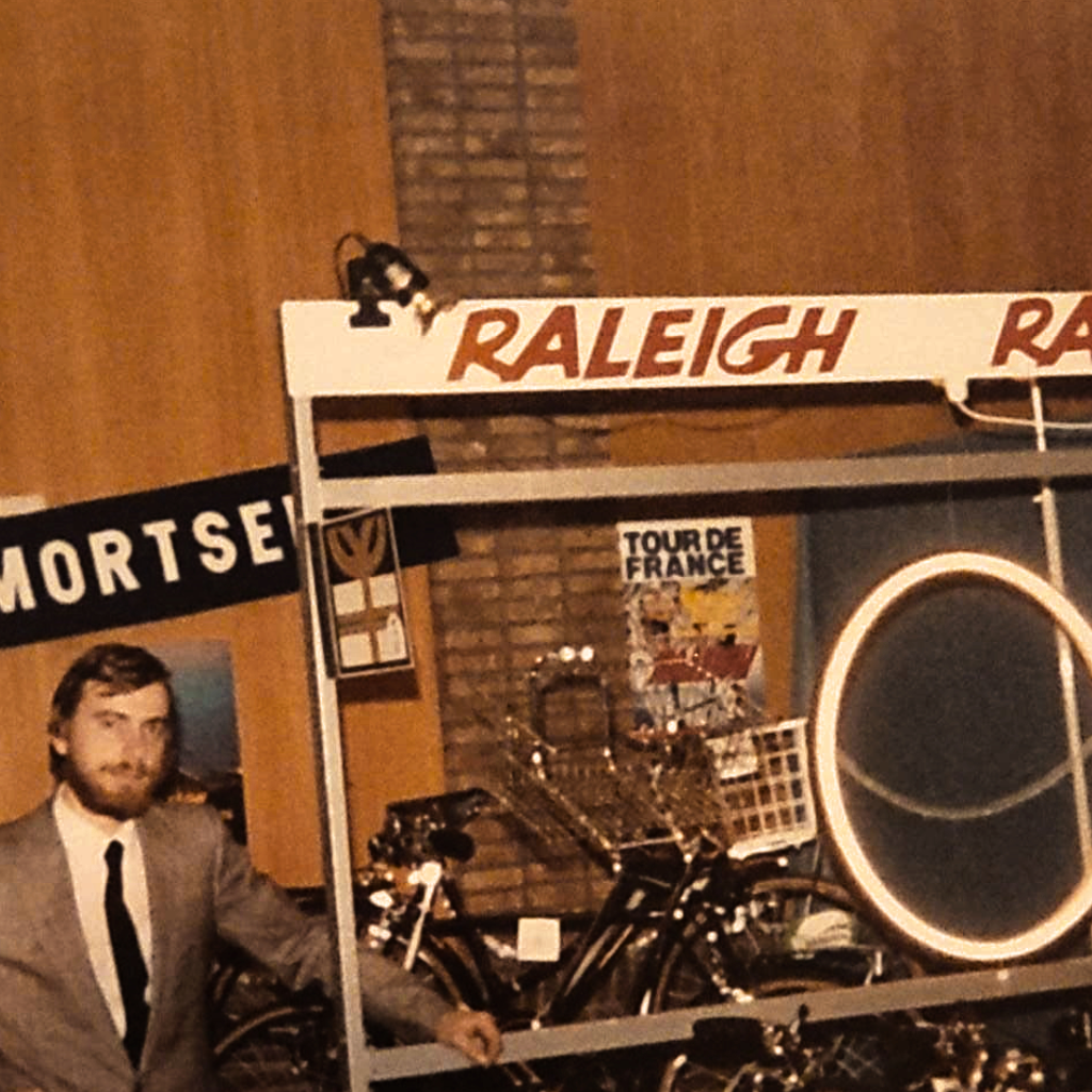 Hier zie je Mattheus Briers op een stand staan van Fietsen MB in de jaren tachtig. Er staat ook een logo van Raleigh op hun stand