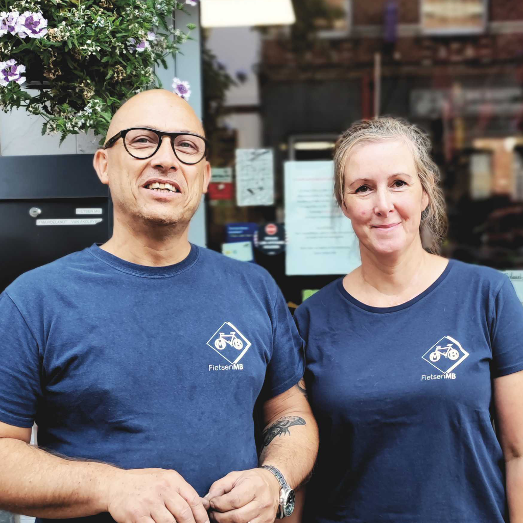 Op deze foto ziet u Michel Roelandt en Wendy Van Akolijen voor Fietsen MB. Ze hebben beiden een blauwe t-shirt aan met daarop het logo van Fietsen MB